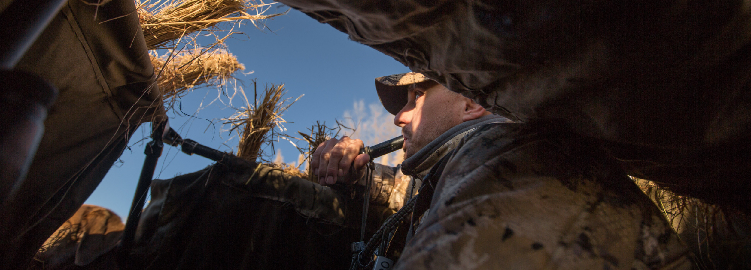 Hunter duck calling in a duck blind.