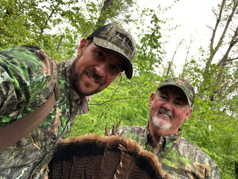 Two turkey hunters smile after a successful hunt